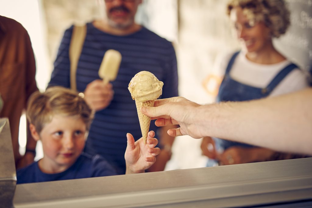 Girl being handed an ice cream in Trebah Boathouse cafe
