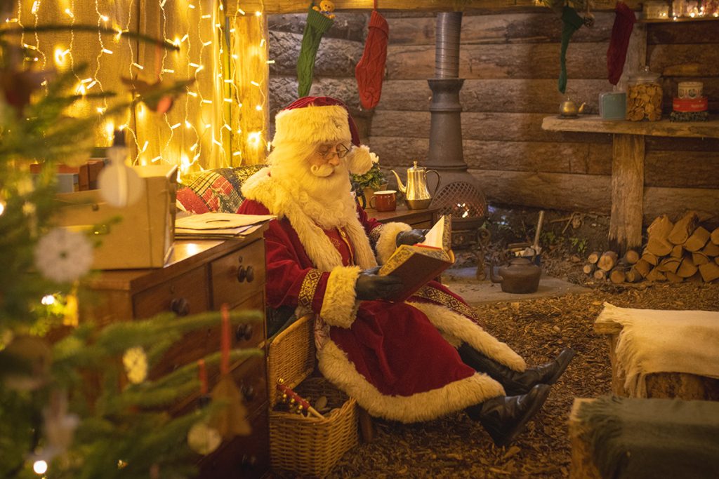 Santa Claus sat in a chair reading a book