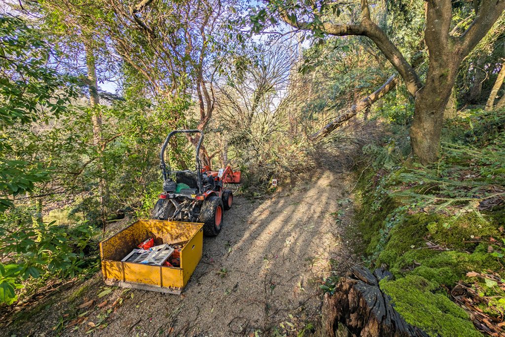 A tractor at trebah garden next to fallen branches