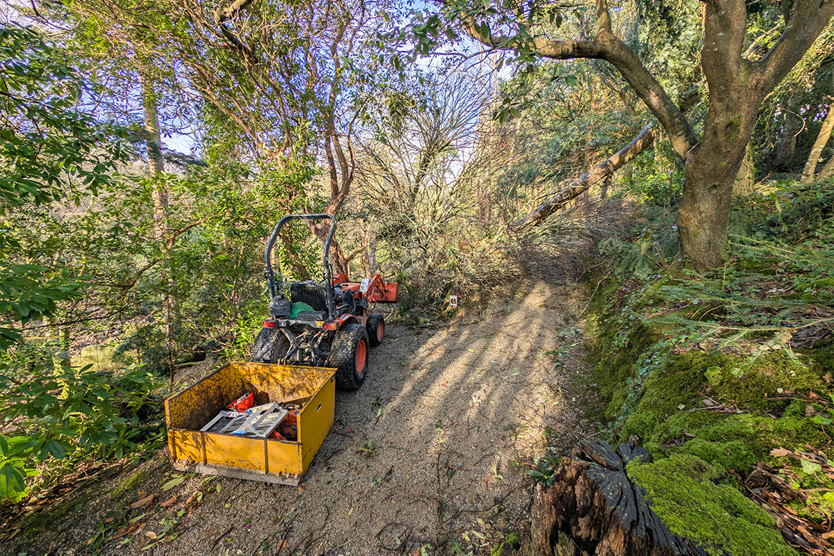 A tractor at trebah garden next to fallen branches