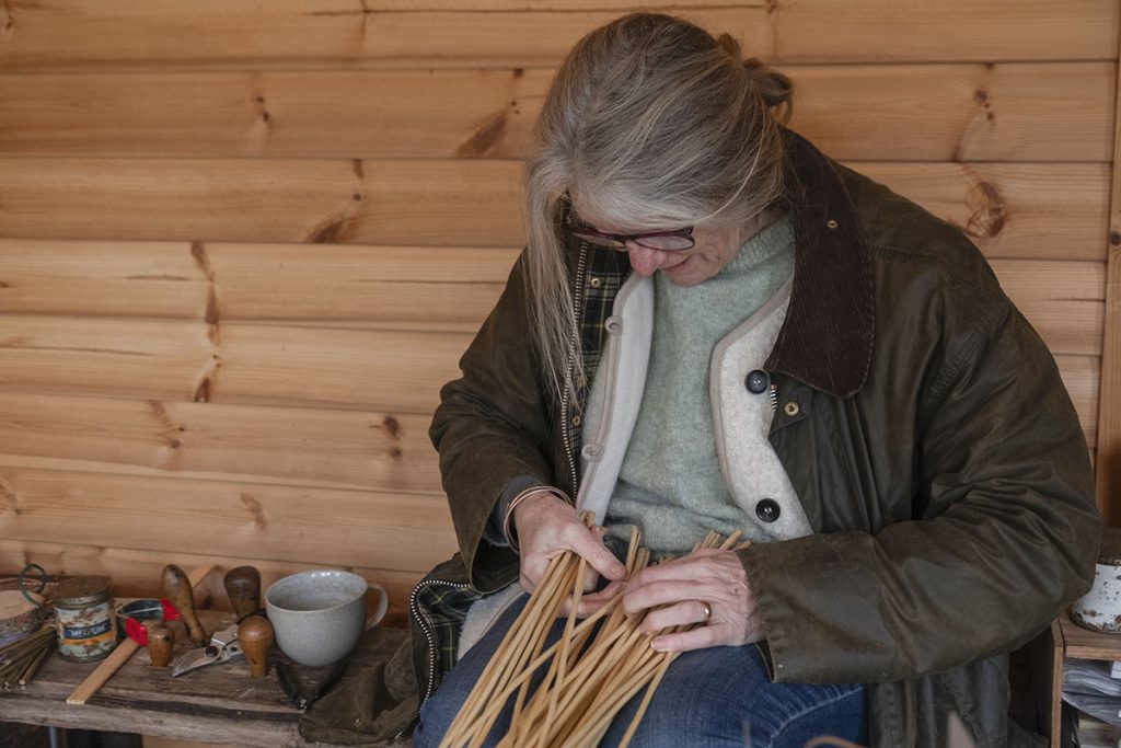Lady sat weaving willow stick together