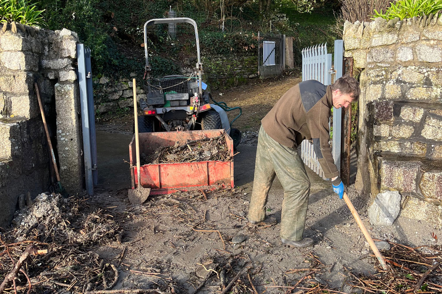 Gardener clearing debris on trebah beach