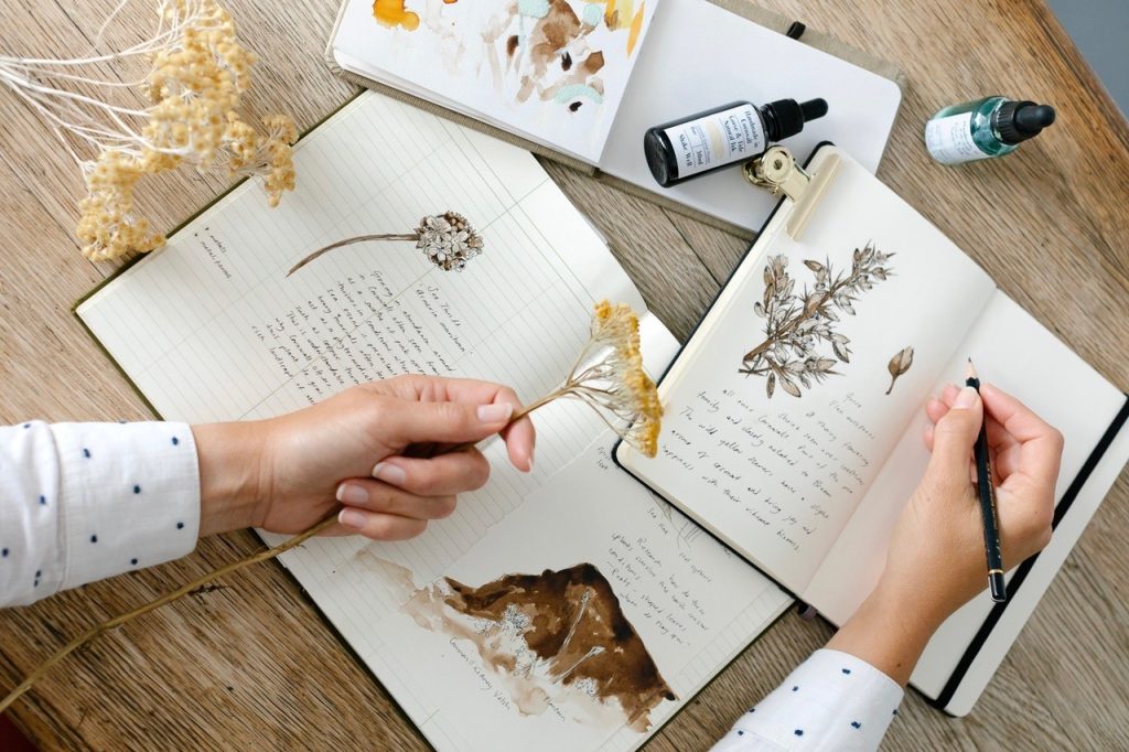 Lady holding a flower and drawing it in a sketch book