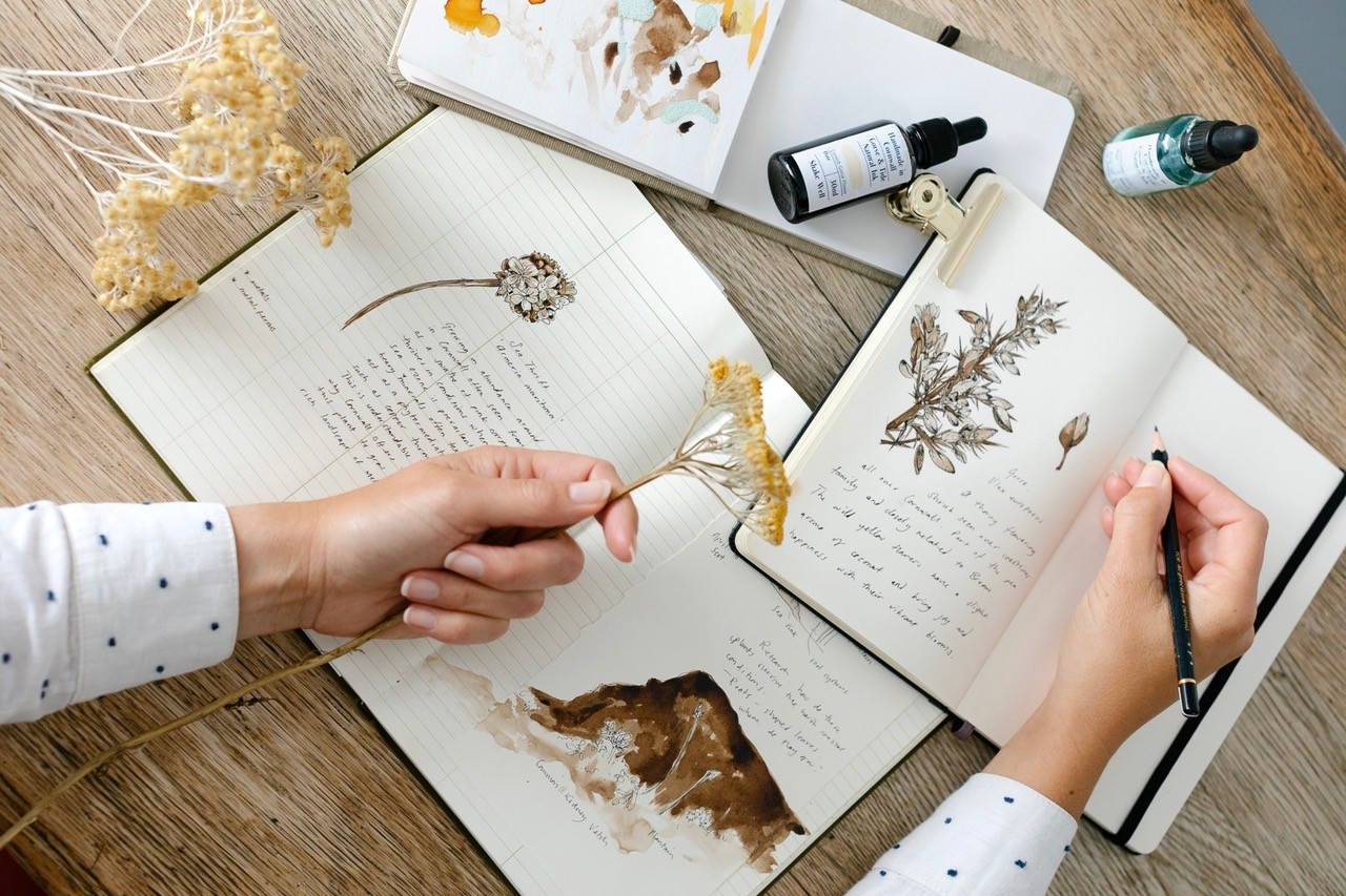 Lady holding a flower and drawing it in a sketch book